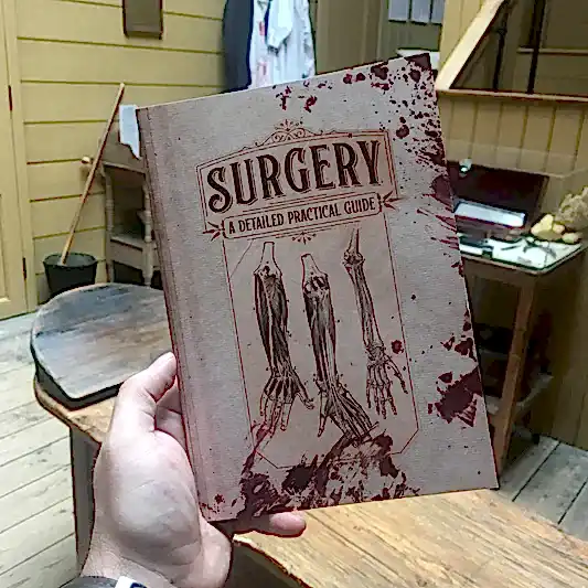 Notebook with illustrations of arm anatomy and blood spatter. Text: Surgery a detailed practice guide